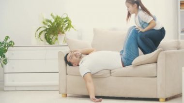 Babası küçük kızıyla oynadıktan sonra 4K yavaş çekim videosunda beyaz koltukta sıralanır..