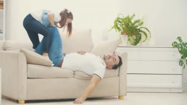 Babası küçük kızıyla oynadıktan sonra 4K yavaş çekim videosunda beyaz koltukta sıralanır..