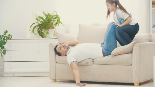 Pai está em camadas depois de jogar com sua filhinha no sofá branco em 4k slow motion vídeo . — Vídeo de Stock