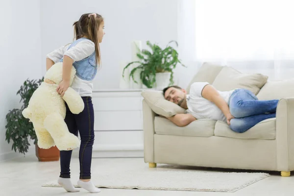 Papa schläft und seine Tochter hält einen weißen Bären. — Stockfoto