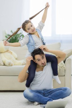 Baba, güzel küçük kızını oturma odasında kucağında tutuyor..