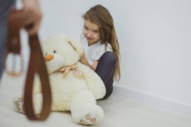 Babanın kemer tutuşu ve korkmuş kızının yerde oturuşu..