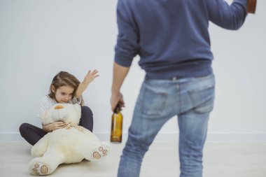 Elinde bira şişesi olan baba, kızına kemerle vuruyor..