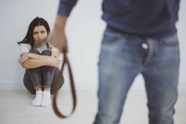 Man threating and beating his wife at home with a belt.