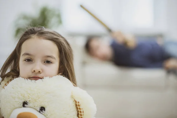 Krásná holčička s tmavými vlasy se dívá přímo do kamery. Dívka sedící na podlaze. — Stock fotografie