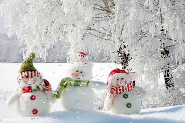Drie sneeuwpoppen in de sneeuw. — Stockfoto