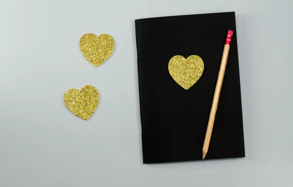 Corazón de oro con un lápiz negro en un plato — Foto de Stock
