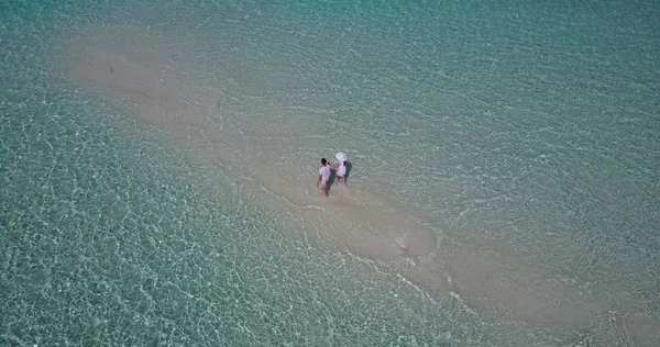 v03925 Aerial flying drone view of Maldives white sandy beach 2 people young couple man woman romantic love on sunny tropical paradise island with aqua blue sky sea water ocean 4k