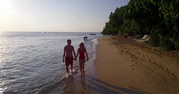 v04140 Aerial flying drone view of Maldives white sandy beach 2 people young couple man woman romantic love sunset sunrise on sunny tropical paradise island with aqua blue sky sea water ocean 4k