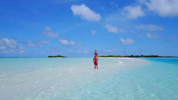 P02567 Aerial flying drone view of Maldives white sandy beach 2 people a young couple man woman walking on sunny tropical paradise island with aqua blue sky sea water ocean 4k