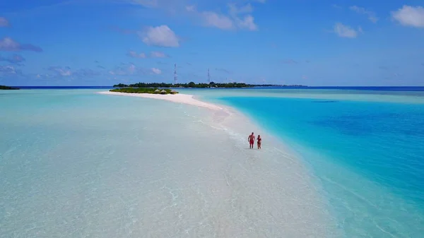 P02570 Aerial flying drone view of Maldives white sandy beach 2 people a young couple man woman walking on sunny tropical paradise island with aqua blue sky sea water ocean 4k