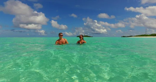 v15486 two 2 people together having fun man and woman together a romantic young couple sunbathing on a tropical island of white sand beach and blue sky and sea