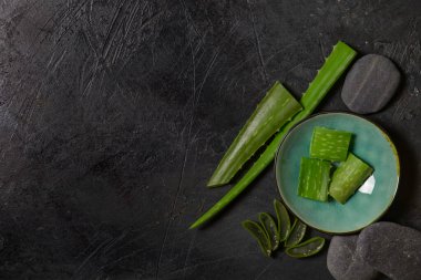 Taze aloe vera üfleyicisi koyu arkaplanda spa taşları ile