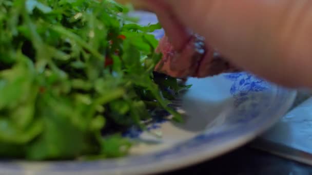 Говядина на тарелке с рукколой — стоковое видео