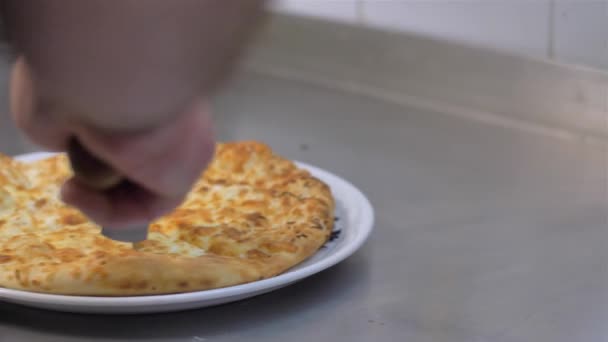Slow motion close-up van een persoon die een peperoni pizza in meerdere plakjes snijdt met een pizzasnijder — Stockvideo