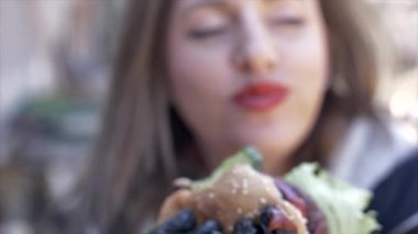 Lastik raavit ile hamburger yiyen kız.