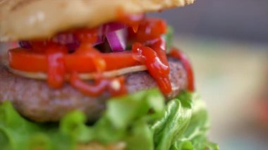 Yavaş hareket eden yiyecek konsepti. Şef hamburger yapıyor. Yakın plan. Burger restoranının menü pişirme işlemi. Şef restoranda fast food hazırlıyor. Siyah ekmeğe peynir sosu döküyor..