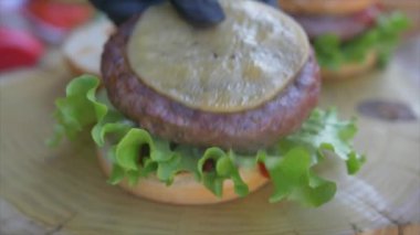 Yavaş hareket eden yiyecek konsepti. Şef hamburger yapıyor. Yakın plan. Burger restoranının menü pişirme işlemi. Şef restoranda fast food hazırlıyor. Siyah ekmeğe peynir sosu döküyor..