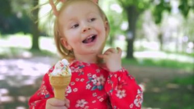 Tatlı küçük bir kız yaz boyunca lezzetli bir dondurma külahının tadını çıkarıyor. Şehir parkında yürüyüş yapan dondurmalı bir çocuk.