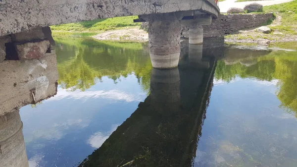 Uma ponte de pedra sobre o rio. Foto debaixo da ponte. Primavera tardia . — Fotografia de Stock