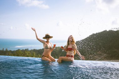 Güzel kızlar havuz kenarında şarapla eğleniyorlar ve seyahat ve hafta sonundan bahsediyorlar. 8 Mart 'ta görüşelim. Tatiller ve deniz kenarındaki bir villada havuz başında partiler. Tayland, Samui