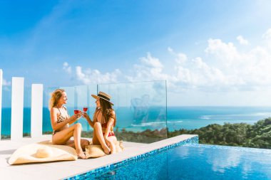 Güzel kızlar havuz kenarında şarapla eğleniyorlar ve seyahat ve hafta sonundan bahsediyorlar. 8 Mart 'ta görüşelim. Tatiller ve deniz kenarındaki bir villada havuz başında partiler. Tayland, Samui