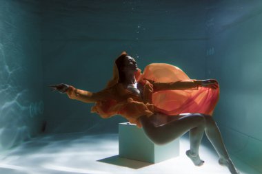 Güzel kız sarı bir elbiseyle suyun altında yüzüyor. 2020 Yeni Yıl trendi Aqua Mente ve fatom blue ve yemyeşil lav. Sualtı kızı denizkızı. Reklam için uygun bir model
