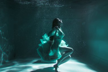 Güzel kız sarı bir elbiseyle suyun altında yüzüyor. 2020 Yeni Yıl trendi Aqua Mente ve fatom blue ve yemyeşil lav. Sualtı kızı denizkızı. Reklam için uygun bir model