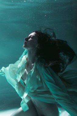 Güzel kız sarı bir elbiseyle suyun altında yüzüyor. 2020 Yeni Yıl trendi Aqua Mente ve fatom blue ve yemyeşil lav. Sualtı kızı denizkızı. Reklam için uygun bir model