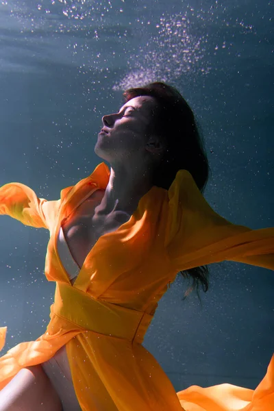 美しい少女は黄色のドレスで水中で泳ぐ 2020新年の傾向アクアメンテと運命青と緑豊かな溶岩 水中の少女人魚 広告に適したモデル — ストック写真