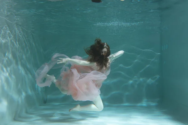 一个黑头发的女孩穿着粉色衣服头戴皇冠在水里游泳 就像一个水下女王 适合做广告的童话故事 — 图库照片
