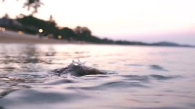 Güzel, ince ve genç bir kız turkuaz denizde yüzüyor. Uzun saç ve modelde ince bir figür. Bir kadın suya dalıyor ve su sıçrıyor. Sakinlik, mutluluk ve rahatlama kavramı..