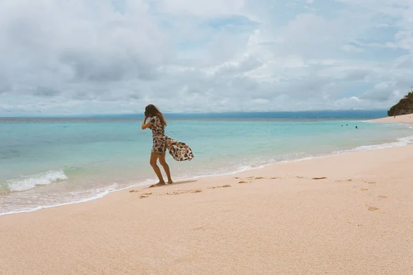 身穿连衣裙的年轻漂亮的姑娘 在大海和大海的海岸上摆姿势 荡漾着蓝色的波浪 穿着长裙 模特儿和时尚造型的女人 巴厘岛的放松和放松 — 图库照片