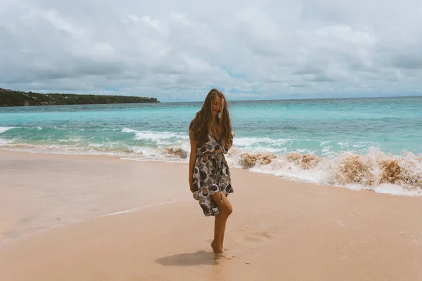 身穿连衣裙的年轻漂亮的姑娘 在大海和大海的海岸上摆姿势 荡漾着蓝色的波浪 穿着长裙 模特儿和时尚造型的女人 巴厘岛的放松和放松 — 图库照片