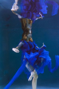 Mavi elbiseli güzel kız havuzda ya da denizde yüzüyor..