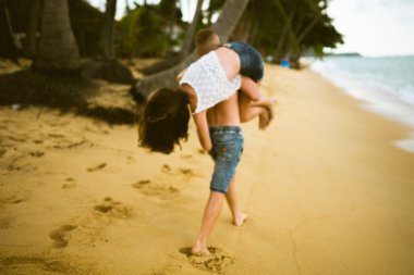 Güzel erkek ve kız koşar ve okyanusta veya denizde sahilde eğlenirler. Karı kocanın tropiklerinde balayı. Ateşli ülkelerde aşk. Kumda yuvarlan ve mutlu ve aşık ol. Aşıklar