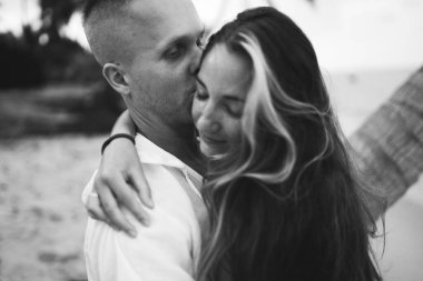 Güzel erkek ve kız koşar ve okyanusta veya denizde sahilde eğlenirler. Karı kocanın tropiklerinde balayı. Ateşli ülkelerde aşk. Kumda yuvarlan ve mutlu ve aşık ol. Aşıklar