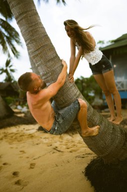 Güzel erkek ve kız koşar ve okyanusta veya denizde sahilde eğlenirler. Karı kocanın tropiklerinde balayı. Ateşli ülkelerde aşk. Kumda yuvarlan ve mutlu ve aşık ol. Aşıklar