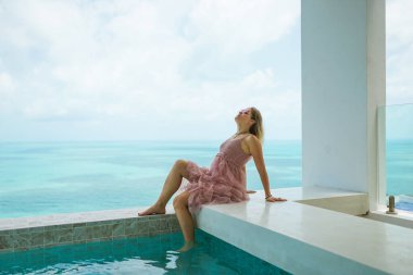 Güzel bir kadın, deniz manzarası ve palmiye ağaçları olan zengin bir villada dinleniyor. Yüz portreleri. İyi tatiller. Egzotik ve tropik bir kızla.