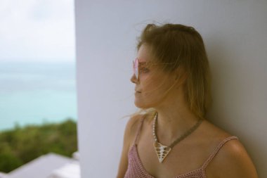 Güzel bir kadın, deniz manzarası ve palmiye ağaçları olan zengin bir villada dinleniyor. Yüz portreleri. İyi tatiller. Egzotik ve tropik bir kızla.