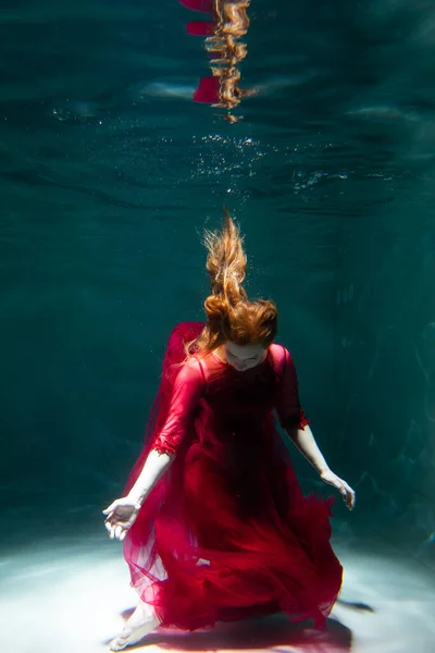 身穿红色衣服的漂亮女孩在游泳池里游泳 温柔和优雅 泡泡和大量的水 — 图库照片