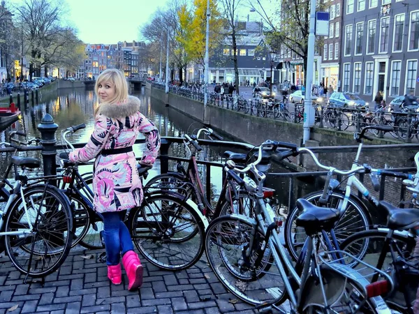 Avrupa kız pembe ceket ve Amsterdam kanal mavi saat (akşam) Bisiklet arasında yakınındaki pembe çizme
