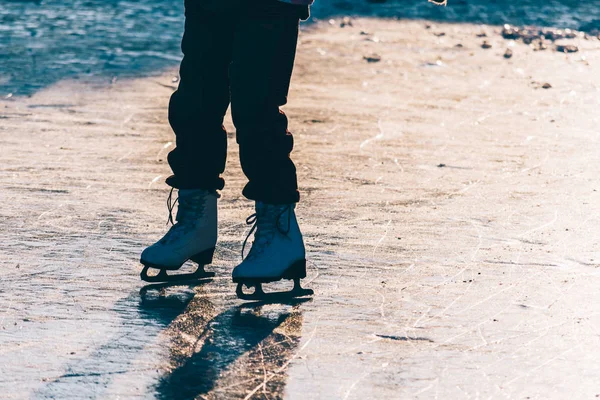 Ein junges Mädchen steht mit Schlittschuhen auf einem zugefrorenen Teich an der — Stockfoto