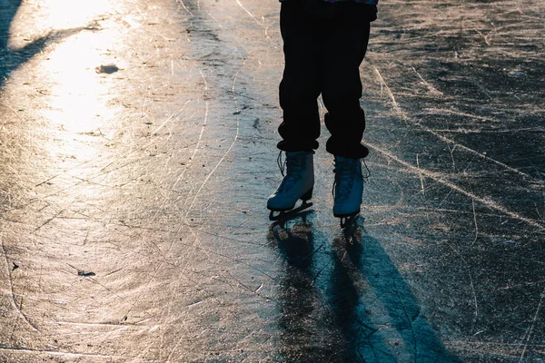 Close-up of woman skating on ice. Close-up of skates and ice. Beautiful winter day.