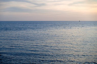 Açık deniz ufkunda küçük bir yelkenli görüntüsü.