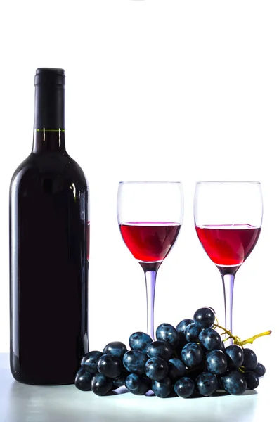Botella de vino tinto, copas de vino y uvas sobre un fondo blanco — Foto de Stock