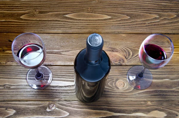 Botella de vino tinto, copas de vino y uvas sobre mesa de madera — Foto de Stock