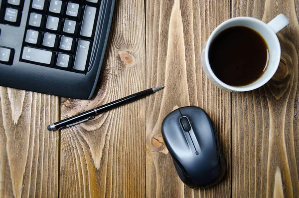 keyboard, pen, mouse, and a cup of coffee on the wooden table.