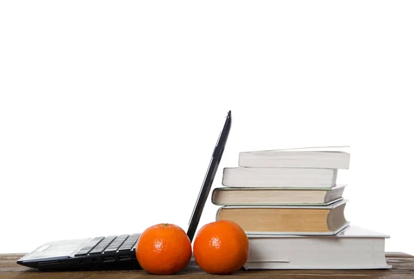 Açık laptop, kitaplar ve mandalina yığını