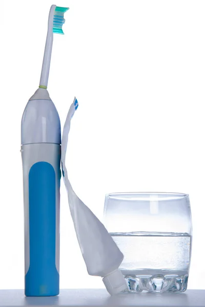 Зубная щетка с зубной пастой и стакан воды на белом фоне — стоковое фото